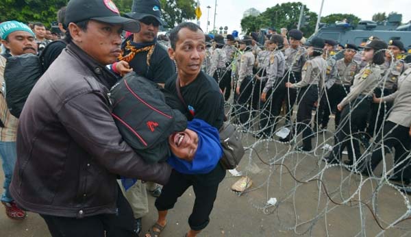 TIGA HARI DEMO: Seorang guru honorer pingsan dan diangkat rekan-rekanya untuk mendapat penanganan kesehatan saat aksi unjuk rasa di depan Istana Merdeka. foto: merdeka.com