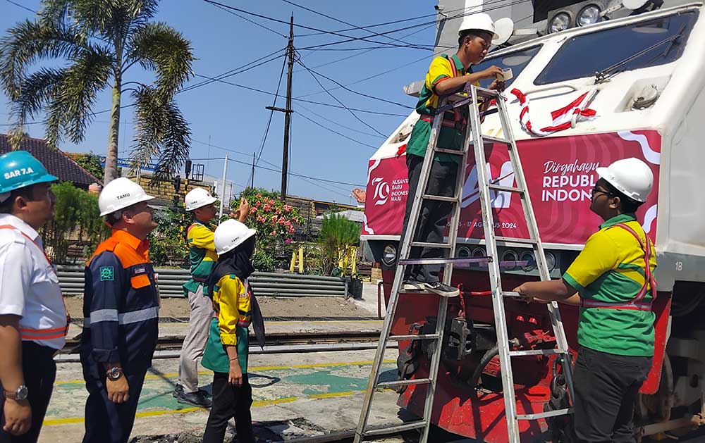 Kepala Daerah Operasi PT PT KAI Daop 7 Madiun, Suharjono, memeriksa pelaksanaan menghias lokomotif. Foto: HENDRO SUHARTONO/ BANGSAONLINE