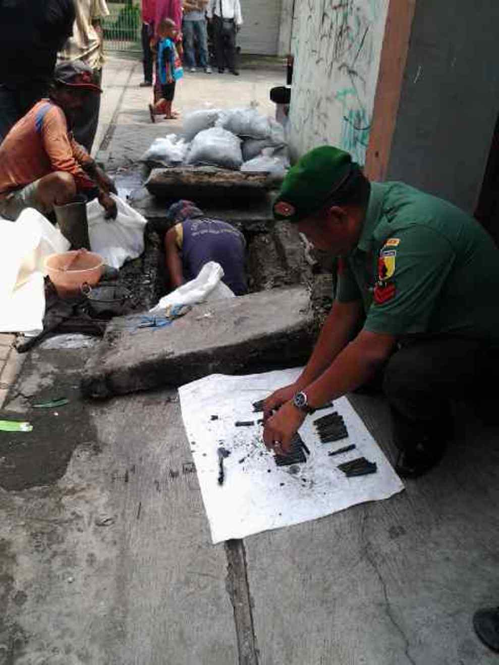Petugas mengevakuasi 46 peluru aktif yang ditemukan di selokan di Jalan KH Mas Mansyur, Surabaya, Selasa (11/3/2014). Foto: Rusmiyanto/Bangsaonline.com