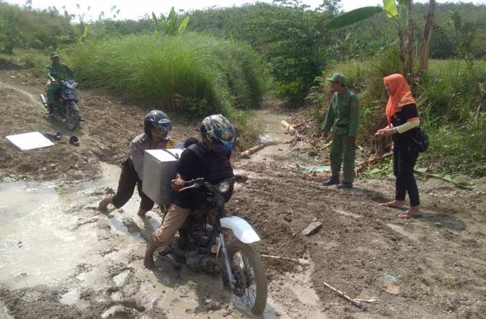 Tampak petugas harus mendorong motor saat melintasi jalanan berlumpur. foto: eki/bangsaonline
