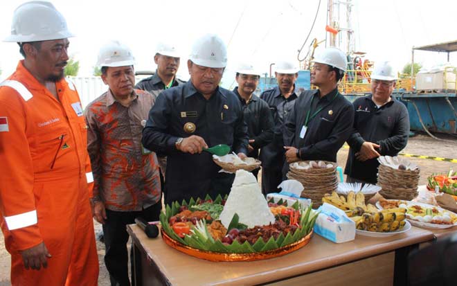 TASYAKURAN: Bupati Sidoarjo H Saiful Ilah memotong tumpeng saat Lapindo memulai workover sumur Wunut 4, di Desa Wunut, Kecamatan Porong, Sidoarjo, Senin (8/8). foto: istimewa