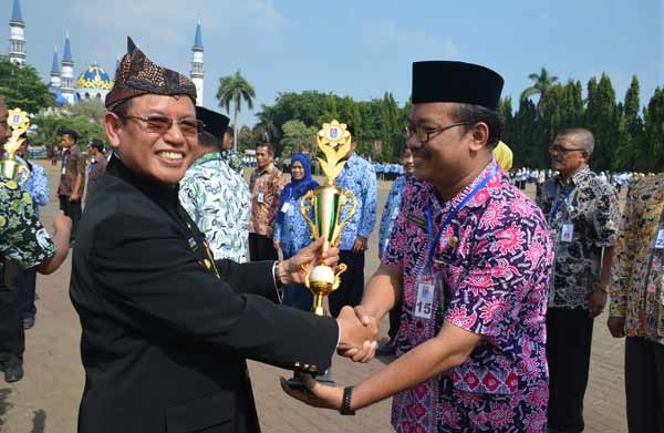 Wakil Bupati Tuban, Ir Noor Nahar Husein saat memberikan piala terbaik I lomba Adiwiyata kepada kepala MAN Tuban, Saifudin Yulianto. foto: suwandi/BANGSAONLINE