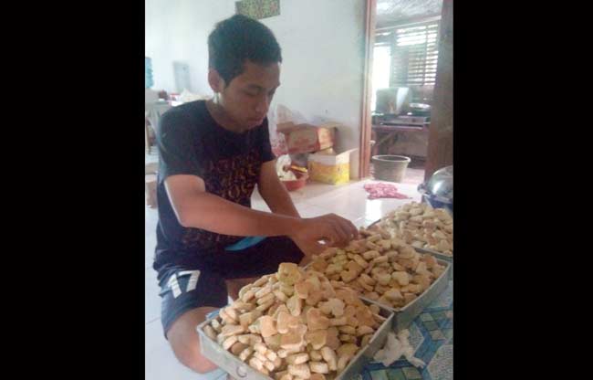 Salah satu anak Muadah saat membantu mengemas kue. foto: EKY NURHADI/ BANGSAONLINE