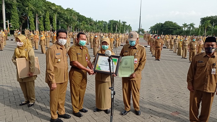 Plt Bupati Gresik Moh. Qosim didampingi Kepala Dinas LH Moh. Najikh menyerahkan piagam Adiwiyata. foto: SYUHUD/ BANGSAONLINE