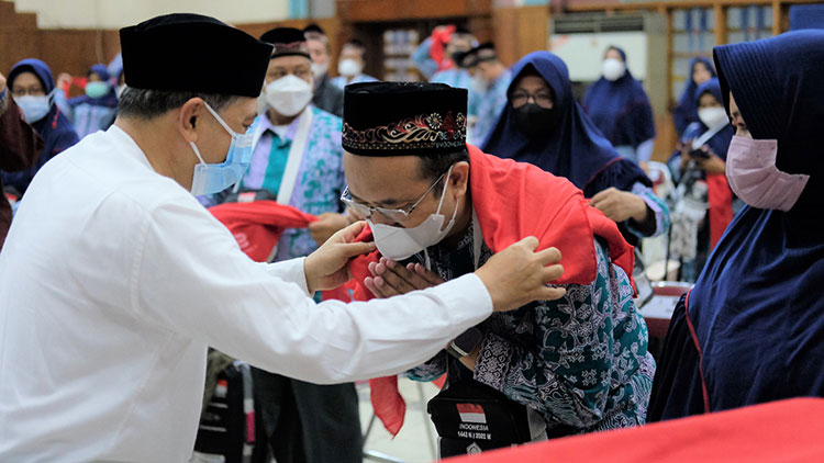 Direktur SDM dan Umum SIG, Agung Wiharto (kiri) menyematkan syal kepada Eko Cahyono, Calon jemaah Haji saat pemberangkatan di Wisma A. Yani, Gresik, Rabu (15/6/2022). Foto: ist.
