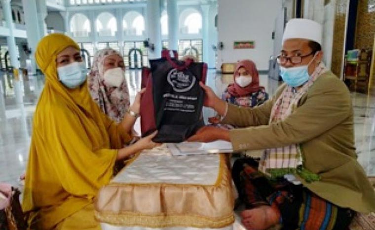 Ustadz Choliq Idris saat menyerahkan cinderamata berupa al-Quran, mukena, dan buku tentang Islam kepada Ika Sari Wijayanti usai ikrar dua kalimat syahadat di Masjid Nasional Al-Akbar Surabaya, Jumat (26/2/2021). Foto: MMA/ BANGSAONLINE.COM