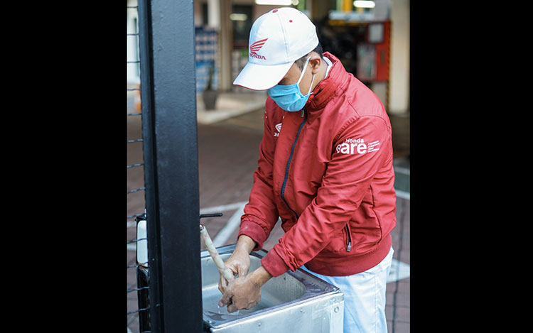 Salah satu sales people saat sedang mencuci tangan sebelum masuk ke area dealer. (foto: ist)