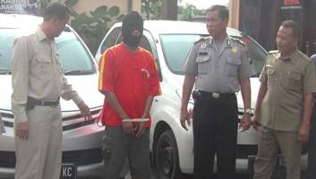 DIAMANKAN – Polisi menunjukkan barang bukti mobil rental dan tersangka Agus Suyanto (pakai penutup wajah) di Mapolres Ngawi. foto: zainal abidin/BANGSAONLINE