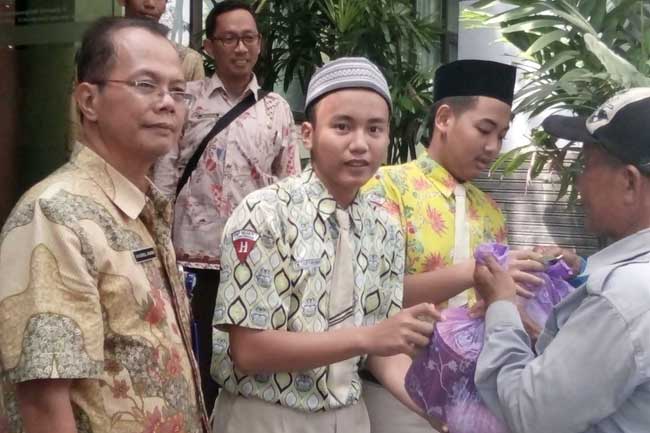 Khoirul Anam, Kasek SMPN 1 mendampingi siswa bagi-bagi sembako.