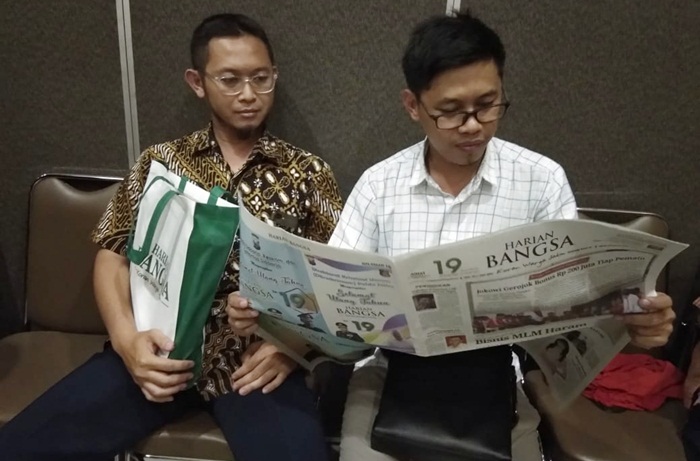 Kasubbid Advokasi dan KIE BKKBN Prov Jatim Toma Afriandi, SH MSi, sedang membaca koran HARIAN BANGSA, ditermani Staf Audio Visual Adetya Surya Y., AMd,. Foto: YUDI ARIANTO/BANGSAONLINE