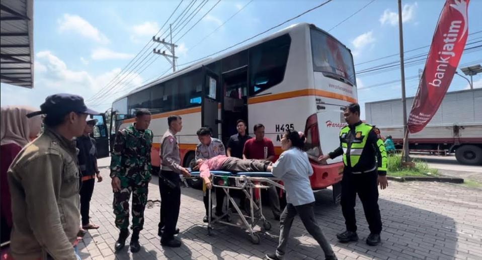 Petugas saat mengevakuasi seorang pemudik yang pingsan dari Bus Harapan Jaya rute Jombang-Mojokerto