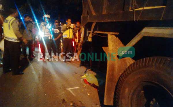Polisi saat melakukan olah TKP dan dump truck yang ditabrak pengendara sepeda motor. foto: suwandi/ BANGSAONLINE