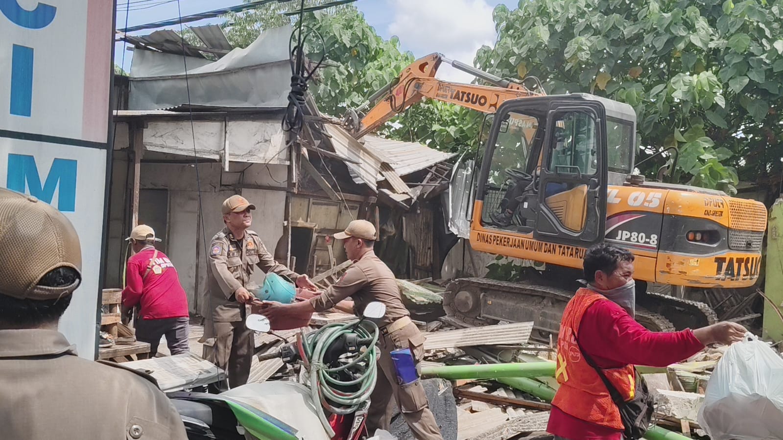 Petugas dengan alat berat membongkar bangli di sempadan saluran air di Dusun Semambung. foto: ist.