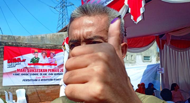 Wahyudi menunjukan jari bertinta usai menggunakan hak pilih. foto: Akina Nur Alana/ BANGSAONLINE