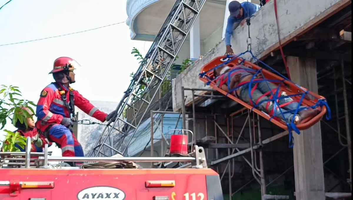 Petugas dari DPKP Surabaya saat mengevakuasi pekerja bangunan yang pingsan.