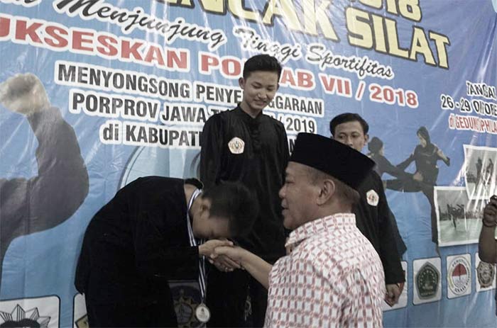 Bupati Fadeli saat mengalungkan medali kepada juara cabor pencak silat. 