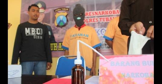 Petugas saat menunjukkan barang bukti berupa alat penghisap (bong), sepoket sabu-sabu, dan tersangka. (Suwandi/BANGSAONLINE)