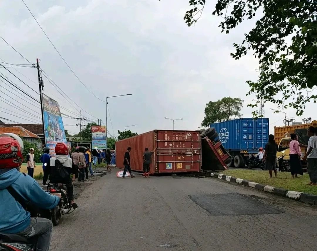 Kondisi truk kontainer yang terguling dan menimpa pemotor di Simpang Balongbendo Timur, Sidoarjo