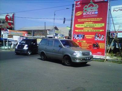 Baliho milik sebuah produk motor di perempatan Jl Raya Dungus melanggar estetika dan mengganggu keselamatan pengguna jalan. foto: daryanto/BANGSAONLINE