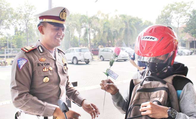 Kasatlantas Polres Pasuruan AKP Evon Fitriyanto sosialisasi Tilang Online dengan cara membagi bunga kepada pengendara.