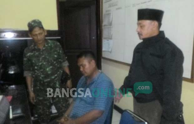 M. Zaini (duduk) tak berkutik saat digelandang warga ke Mapolsek Kadur. foto: ERRI SUGIANTO/ BANGSAONLINE