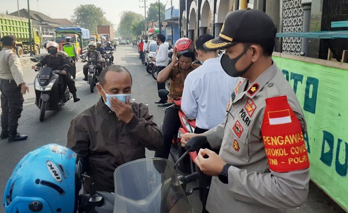 Wakapolres Pasuruan Kompol Muhammad Haris sedang memasang masker pada salah seorang pengguna jalan.