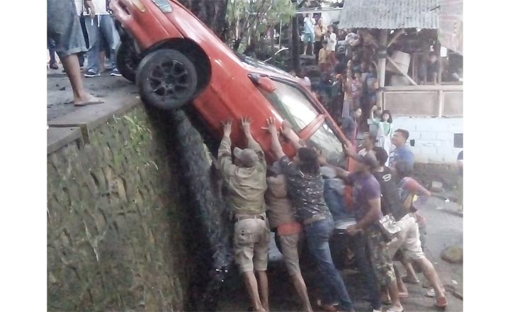 Kondisi mobil sedan yang terperosok saat berusaha dievakuasi oleh warga.