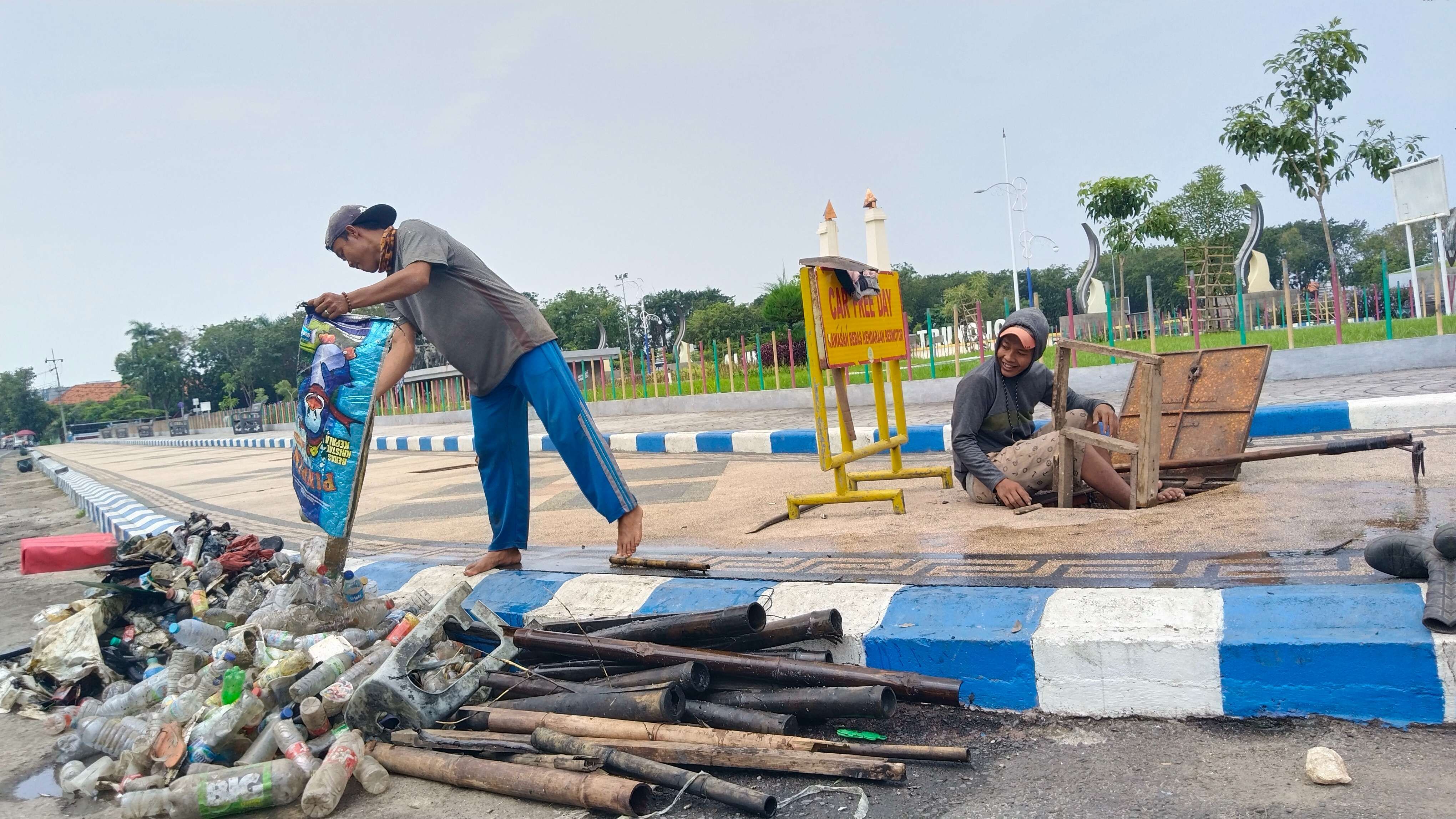 Seorang petugas menuang sampah yang berhasil di keluarkan dari gorong-gorong yang tersumbat di Alun-alun Trunojoyo. (dok. RRI)