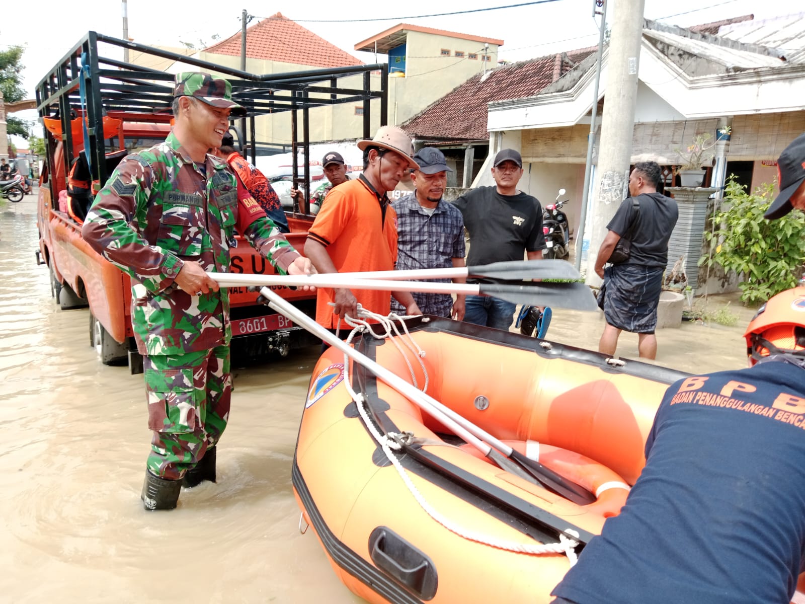 Petugas BPBD Gresik dan Bhabinkamtibmas saat menyiapkan perahu karet untuk evakuasi korban banjir luapan Kali Lamong. Foto: Ist.