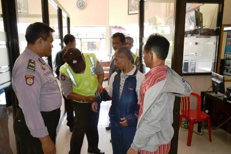 Polisi melepas borgol dari pergelangan tangan pejudi, sebelum dimasukkan ke dalam sel. Foto:Aris Yudisantoso/BANGSAONLINE
