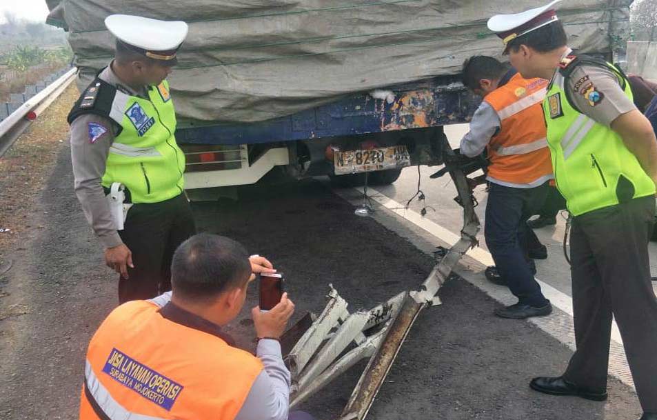 Petugas memeriksa bagian belakang truk yang diseruduk mobil korban. foto: Syuhud/ bangsaonline
