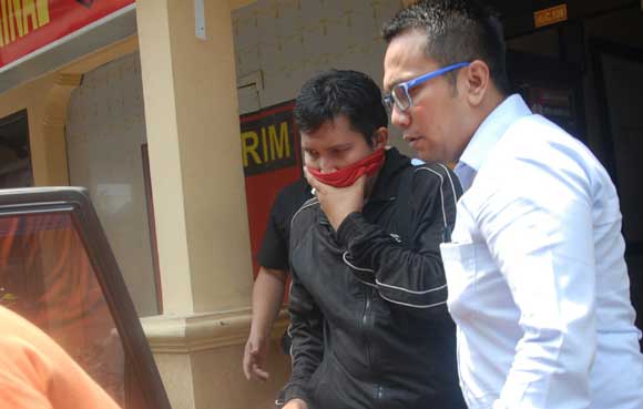 Kepala Satuan Reserse Kriminal (Satreskrim) Polres Jombang, AKP Wahyu Hidayat saat menggelandang tersangka (baju hitam) masuk ke dalam mobil. foto: rony suhartomo/BANGSAONLINE