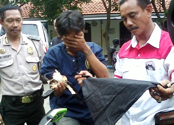 Kanit Reskrim Kenjeran menenteng jimat milik pelaku. Foto:rusmiyanto/BANGSAONLINE
