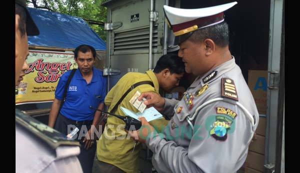 Petugas kepolisian saat memeriksa barang bawaan kendaraan roda empat yang melintas di jalan Ahmad Yani Kota Kediri. foto: arif kurniawan/ BANGSAONLINE