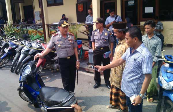 SENANG: Suratman (pakaian kuning) tampak senang saat menemui sepeda motornya yang hilang sebak lima belas bulan yang lalu. foto: Eky Nurhadi/BANGSAONLINE