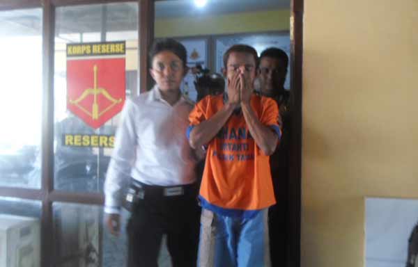 Tersangka Gaguk Hadi Prasetyo menutupi wajahnya saat digelandang ke Mapolsek Taman. foto: catur andy herlambang/BANGSAONLINE