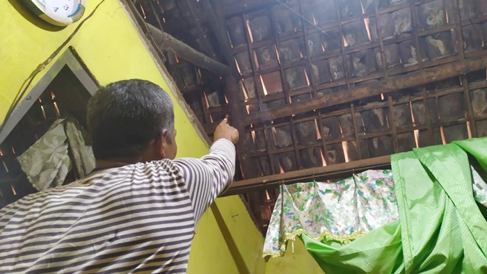 Suparno saat menunjukkan lokasi lemparan batu pada genting dapurnya.