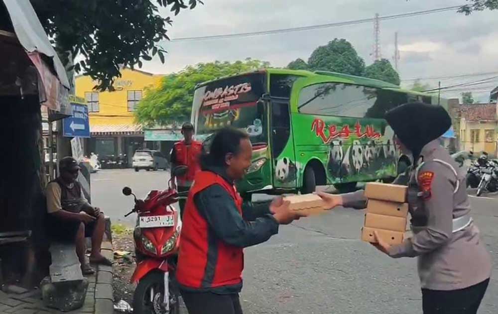 Anggota Polwan Polres Pasuruan saat membagikan nasi kotak kepada salah satu tukang ojek. 