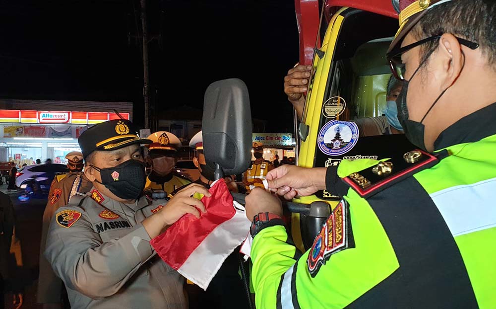 Kapolresta Banyuwangi AKBP Nasrun Pasaribu (kiri) saat mengikat bendera merah putih ke spion salah satu truk logistik.