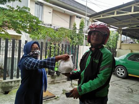 Umi Tutut, bagian pemasaran HARIAN BANGSA menyerahkan sedekah rutin HARIAN BANGSA kepada ojek online di depan kantor HARIAN BANGSA Jalan Gayungsari Surabaya, Jumat (3/4/2020). foto: BANGSAONLINE.COM  