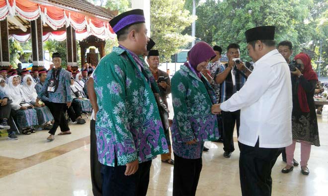 SIMBOLIS: Bupati H Saiful Ilah memasangkan baju batik kepada Jemaah Calon Haji (JCH) Sidoarjo, di Pendopo Delta Wibawa, Sabtu (20/8). foto: MUSTAIN/ BANGSAONLINE.com
