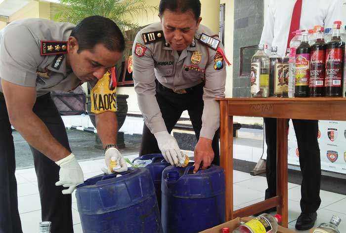 Petugas menunjukkan barang bukti miras yang berhasil disita. foto: AKINA/ BANGSAONLINE