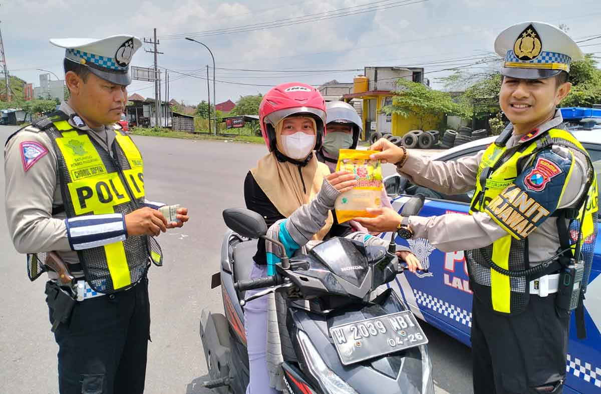 Kanit Turjawali Satlantas Polres Pasuruan, Ipda Hendik Arianto, saat memberikan sembako kepada salah satu pengendara yang tertib berlalu lintas.