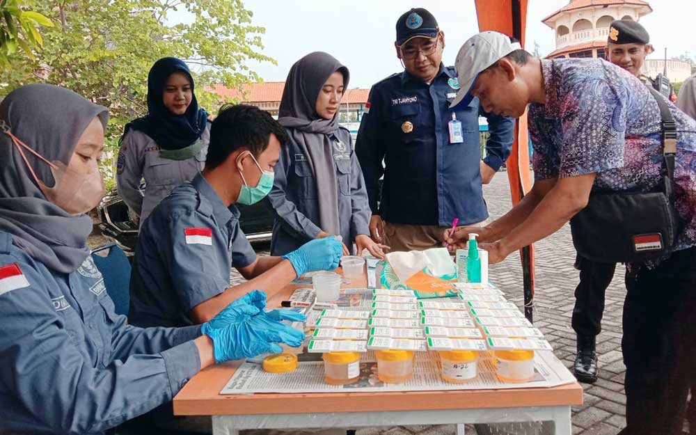 Satu per satu sopir bus menyerahkan sampel urine untuk dites.