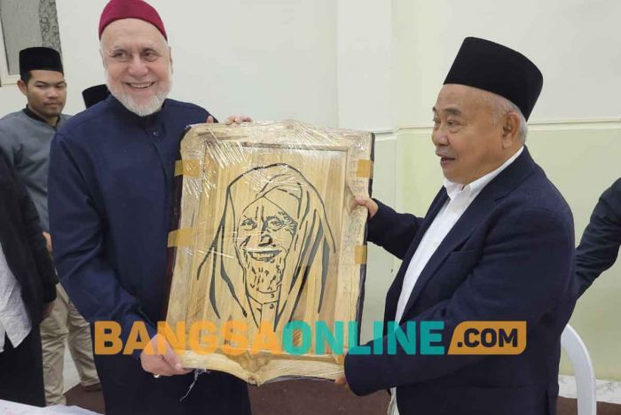 Prof Dr KH Asep Saifuddin Chalim, MA, memberikan cenderamata lukisan kepada Prof Dr Syaikh Muhammad Abdus Shomad Muhanna, penasehat Iman Besar Al Azhar dan ahli hukum internasional yang sangat populer dan berpengaruh di Mesir.  Kiai Asep memberikan cenderamata itu di kediaman Syaikh Muhanna di  Kairo, Mesir, Ahad (8/1/2023) malam. Foto: MMA/ BANGSAONLINE
