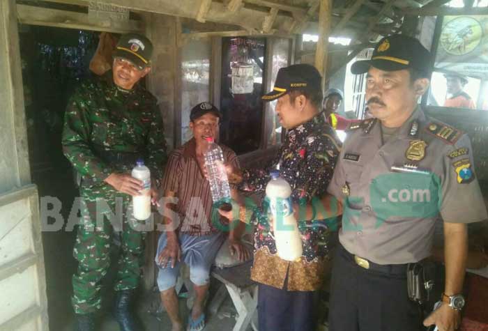 Petugas menunjukkan hasil tangkapan miras jenis arak dan toak. foto: GUNAWAN/ BANGSAONLINE