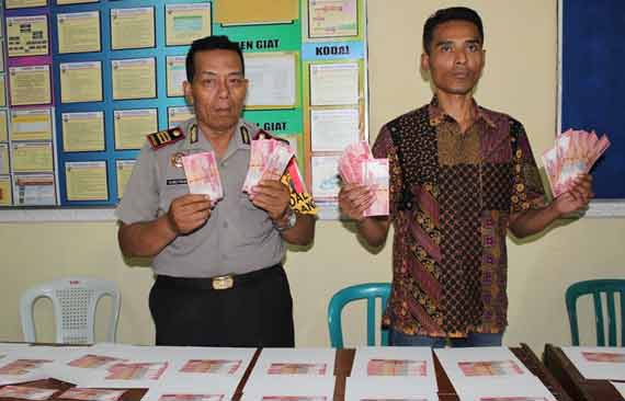 TAK BERTUAN: Kapolsek Gedangan AKP Sutrisno menunjukkan barang bukti (BB) uang palsu (upal) sebanyak 195 lembar dengan pecahan 100 ribuan senilai Rp 19,5 juta. foto: catur andy erlambang/BANGSAONLINE