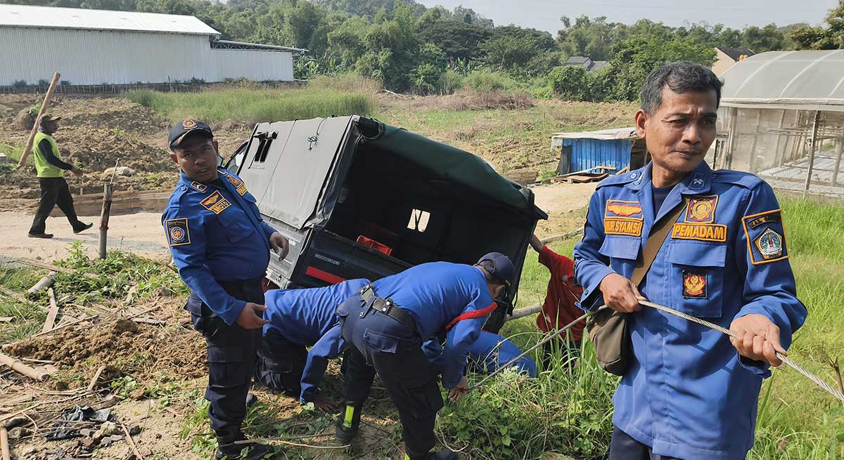 Petugas Damkar Gresik saat evakuasi pikap yang terperosok di pekarangan. Foto: Ist