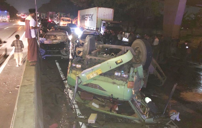 Truk trailer yang terguling berikut tiga mobil yang hancur terkena imbasnya.
