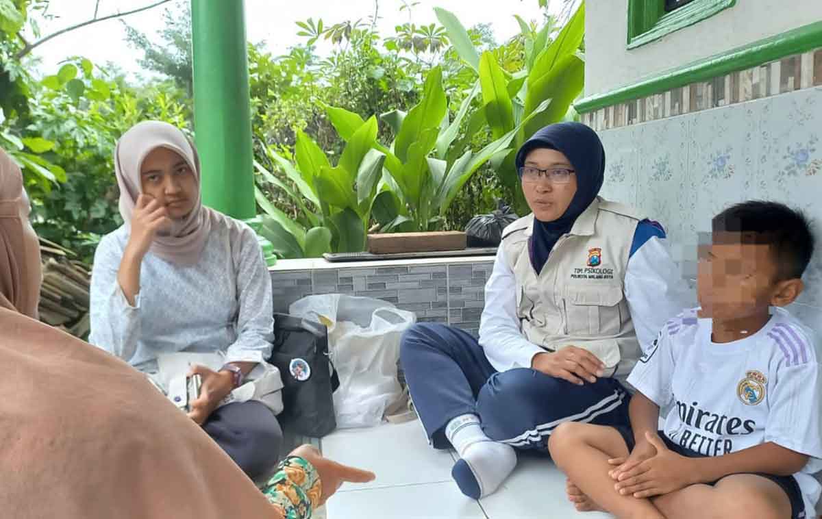 Petugas dari Satgas Polresta Malang Kota bagian Trauma Healing saat memberi bantuan psikologis kepada seorang bocah laki-laki berinisal P (7 tahun) dari Kelurahan Tlogowaru, Kecamatan Kedungkandang.